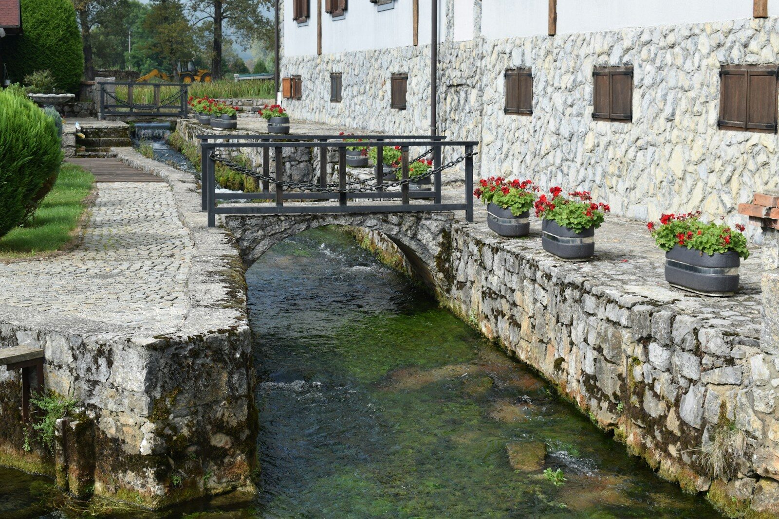 A stone bridge over a small stream in front of a building